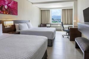 a hotel room with two beds and a desk at Crowne Plaza Airport by IHG in Tocumen