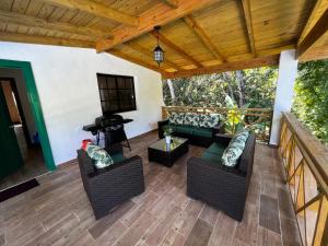 Villa unter Palmen في جاراباكو: شرفة مع كراسي وأريكة وبيانو