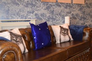 a brown leather couch with pillows on it at The Plough Inn in Stalisfield