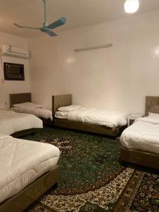 a room with three beds and a rug at Madinah Anbariah in Medina