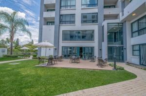 a building with tables and chairs and an umbrella at The Regency Cosy Apartment- 419 in Pretoria