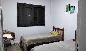 1 dormitorio con 2 camas individuales y ventana en Tenda Caiu do Céu, en Osório