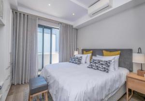 a white bedroom with a large bed and a window at The Regency Cosy Apartment- 419 in Pretoria +12 photos