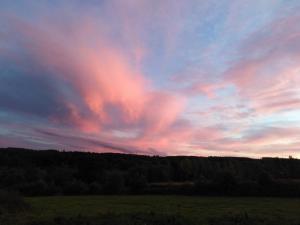 een kleurrijke hemel bij zonsondergang met een veld en bomen bij Relais Du Boss in Saint-Vran
