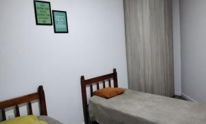 1 dormitorio con 2 camas y 2 cuadros en la pared en Tenda Caiu do Céu, en Osório
