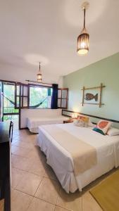 a bedroom with two beds and a large window at Pousada Vila dos Passaros in Itacaré