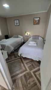 1 dormitorio con 2 camas y suelo de madera en CABAÑA M&M en El Calafate
