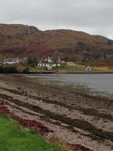 a body of water with houses and mountains in the background at Poolewe Hotel in Poolewe