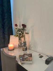 a table with a vase of roses and a candle and a book at Suitedream Vatican in Rome