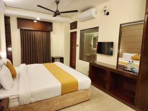a hotel room with a bed and a television at White Park Hotel & Suites in Chittagong