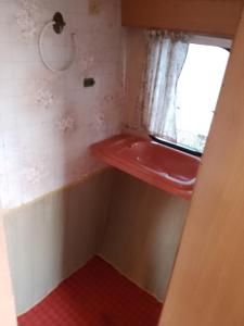 een badkamer met een rode wastafel en een raam bij Retro caravan 