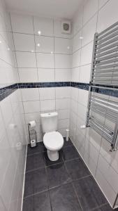 a bathroom with a toilet in a white tiled room at Rutland Point Studio serviced accommodation Keystones Property Services in Morcott