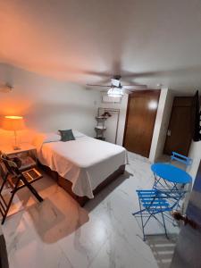 a bedroom with a bed and two blue chairs at Hosteleria Casa Margarita in Mazatlán