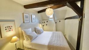 a bedroom with a white bed and a chandelier at La Dolce Vita in Beaune