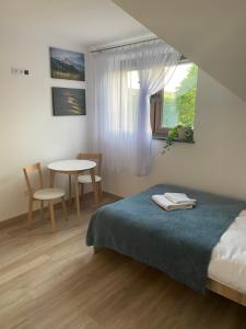 W Pieninach pokoje في سروموس وايزين: غرفة نوم بسرير وطاولة ونافذة