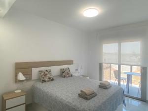 a white bedroom with a bed with two towels on it at Moderno apartamento a 200m de la playa in Torrevieja +12 photos