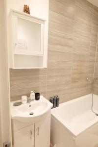 a bathroom with a white sink and a bath tub at Milton Keynes Love Home in Bletchley