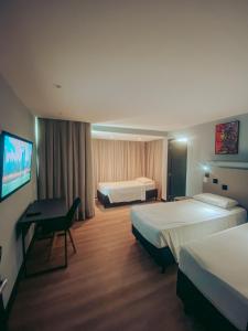 um quarto de hotel com duas camas e uma secretária em Dublê Hotel - The Original em Recife