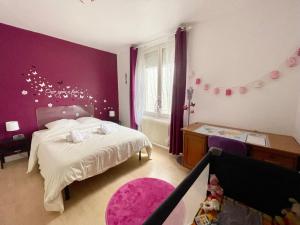 - une chambre avec un lit et un mur violet dans l'établissement La Casa - Charmante maison entre Paris & Disney, à Noisy-le-Grand