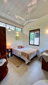 a bedroom with a bed and two windows at Awake Uvita in Uvita