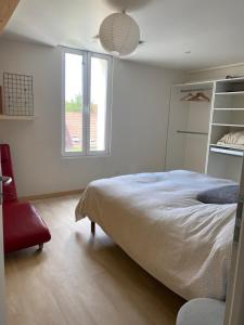 een witte slaapkamer met een bed en een raam bij La maison Familiale in Dijon