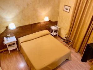 a small bedroom with a yellow bed and two tables at Roma Castle Termini in Rome