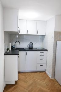 Biała kuchnia z białymi szafkami i drewnianą podłogą w obiekcie ClickTheFlat Three Crosses Square Apart Rooms w Warszawie