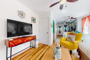 a living room with a tv and a yellow chair at Egret House in Key West