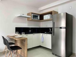 a kitchen with a stainless steel refrigerator and a table at AP1422 ar condicionado piscina academia coworking etc in Juiz de Fora