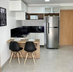 a kitchen with a stainless steel refrigerator and two chairs at AP822 ar condicionado piscina academia coworking etc in Juiz de Fora