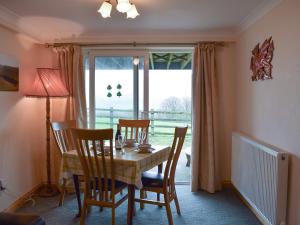 a dining room with a table and chairs and a window at Penybryn in Llansadwrn