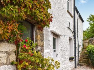 a stone house with flowers on the side of it at Kiln Cottage in Bolton le Sands