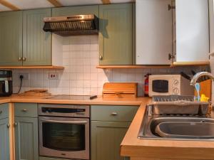 una cocina con armarios verdes y fregadero en Kiln Cottage, en Bolton le Sands