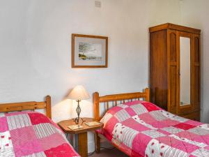 a bedroom with two beds and a table with a lamp at Kiln Cottage in Bolton le Sands