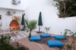 eine Terrasse mit blauen Kissen, einem Tisch und einem Sonnenschirm in der Unterkunft Tranquilo Boutique Hostel - Dahab in Dahab