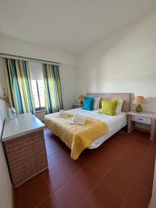 um quarto com uma cama grande com almofadas amarelas e azuis em Residence Golf-Vilamoura! em Quarteira