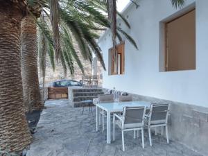 a table and chairs on a patio with a palm tree at La Casita a 60 pasos del mar in Tamaduste