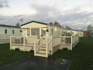 a white house with a porch and a fence at 2 and 3 Bedroom caravans with Hot Tubs at tattershall in Tattershall