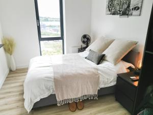 a bedroom with a bed with white sheets and a window at Luxe Apartment: 3 mins Luton Airport & Free Wi-Fi in Luton