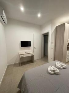 een witte slaapkamer met een bed en een televisie bij Casa vacanze Soraja in Palermo
