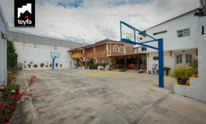 um parque de estacionamento vazio com um cesto de basquetebol em frente a um edifício em TEYFA Hospedaje - Casa em Atuntaqui