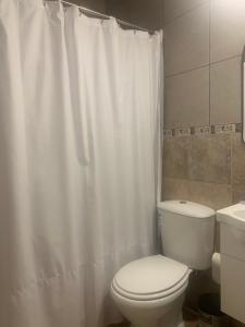 a bathroom with a toilet and a white shower curtain at Sweet Home in Vicente López