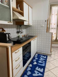 a kitchen with white cabinets and a blue rug on the floor at La Libellula in Ortona