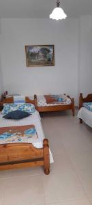 Habitación con 3 camas y una foto en la pared. en Sanos GardenApartament, en Sarandë