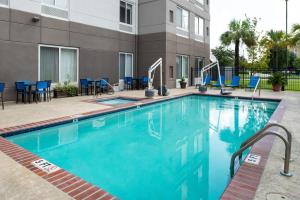 a swimming pool with blue chairs and a building at Hilton Garden Inn Baton Rouge Airport in Baton Rouge