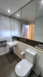 a bathroom with a toilet and a sink and a mirror at Penthouse-level Waterfront Apartment in Darwin