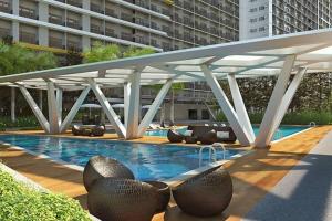 a swimming pool with chairs and a large building at Chic 2 BR EDSA APT w/ Balcony Netflix Prime Video in Manila