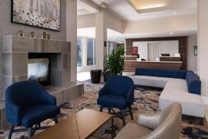 a living room with blue chairs and a fireplace at Hilton Garden Inn Baton Rouge Airport in Baton Rouge