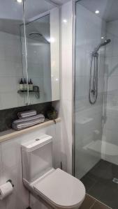 y baño blanco con aseo y ducha. en Penthouse-level Waterfront Apartment en Darwin