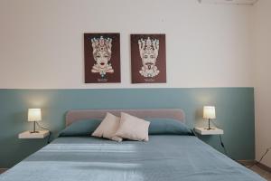 a bedroom with a bed with three pictures on the wall at Makira in Terrasini